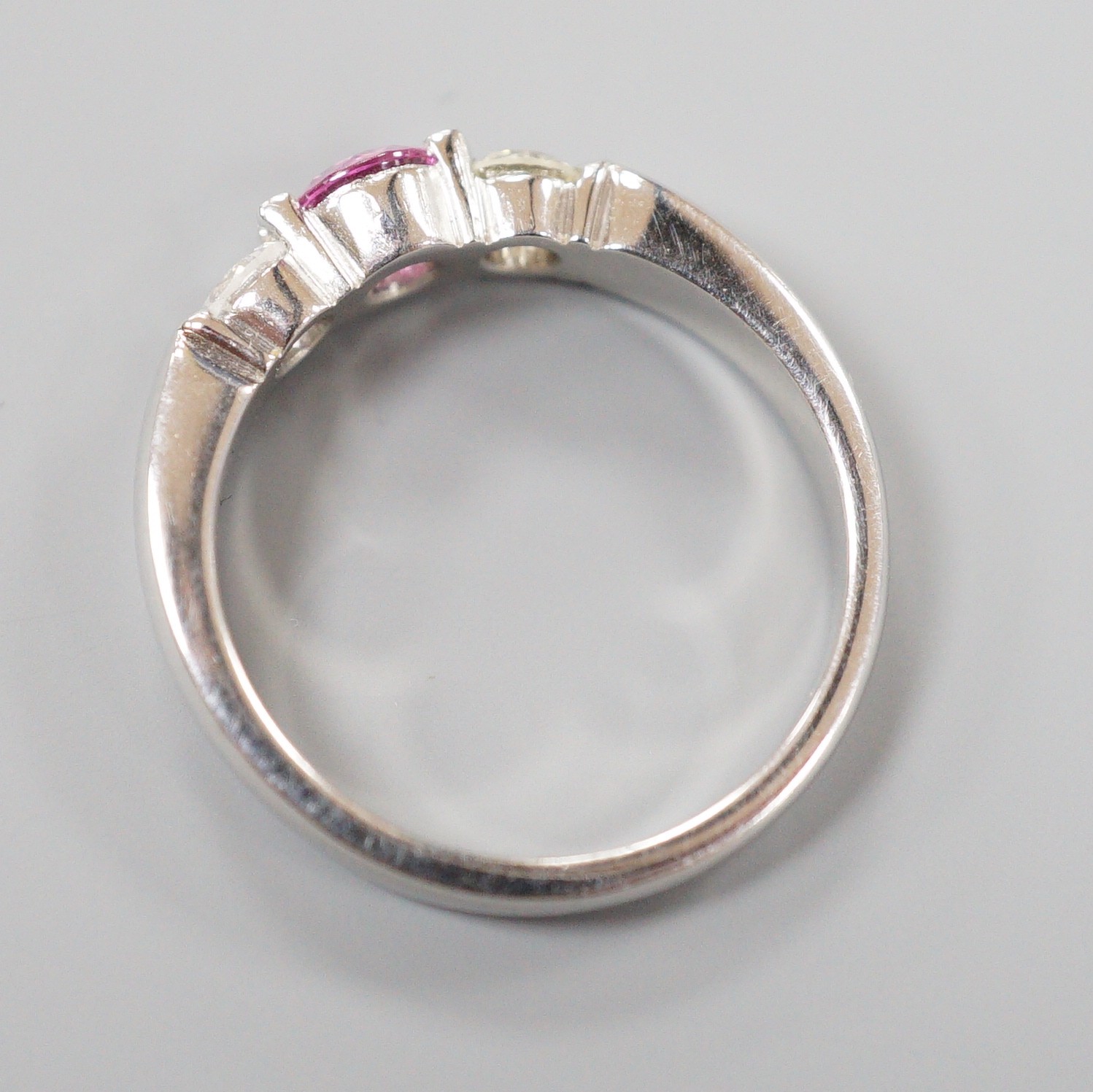 A modern platinum, single stone pink sapphire and two stone diamond set ring, size M/N, gross weight 6.5 grams